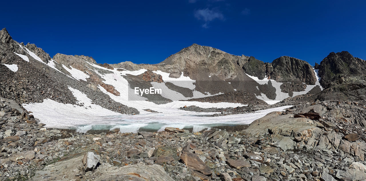 Scenic view of snowcapped mountains against blue sky