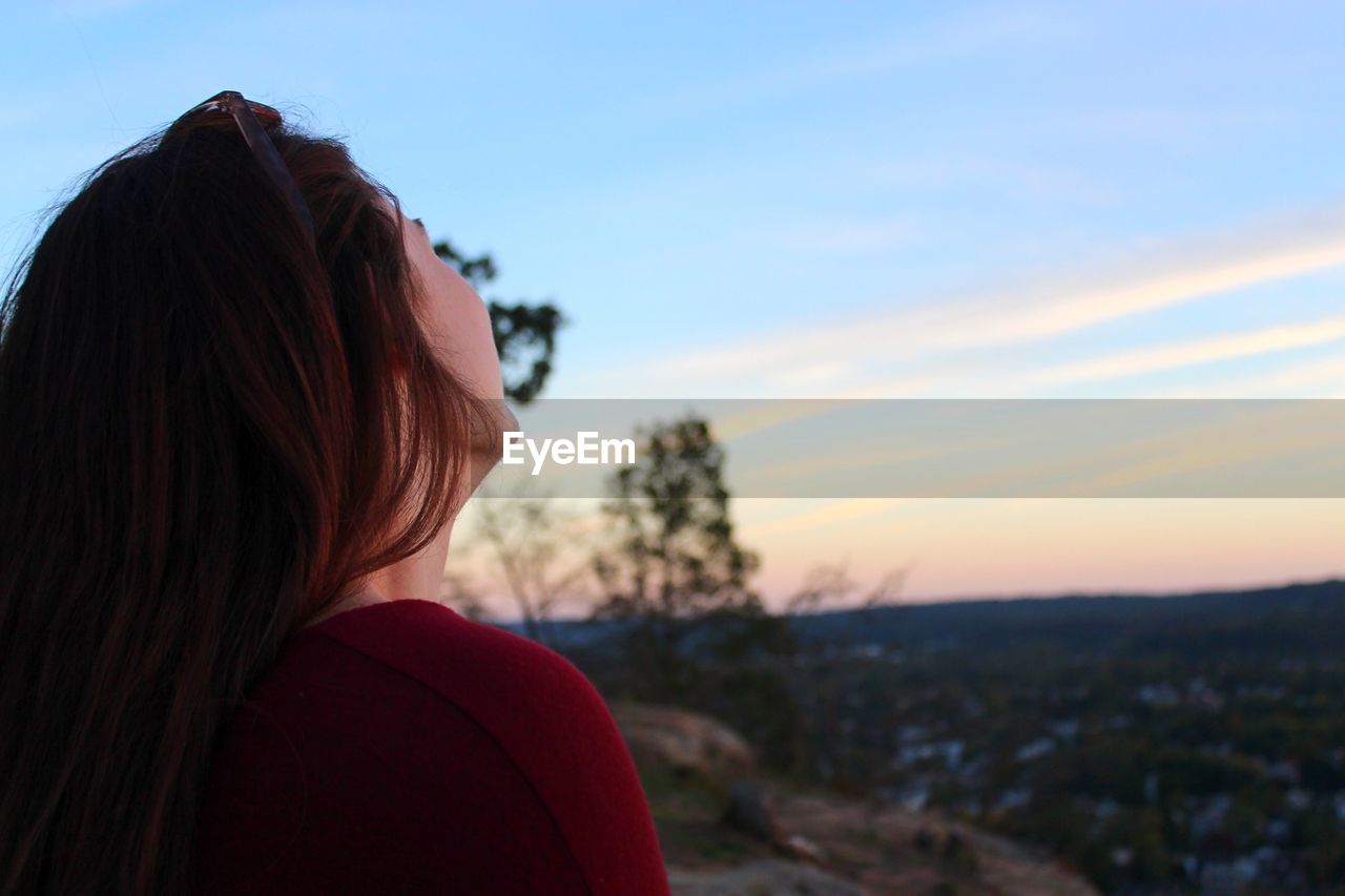 Redhead woman on landscape against sky during sunset