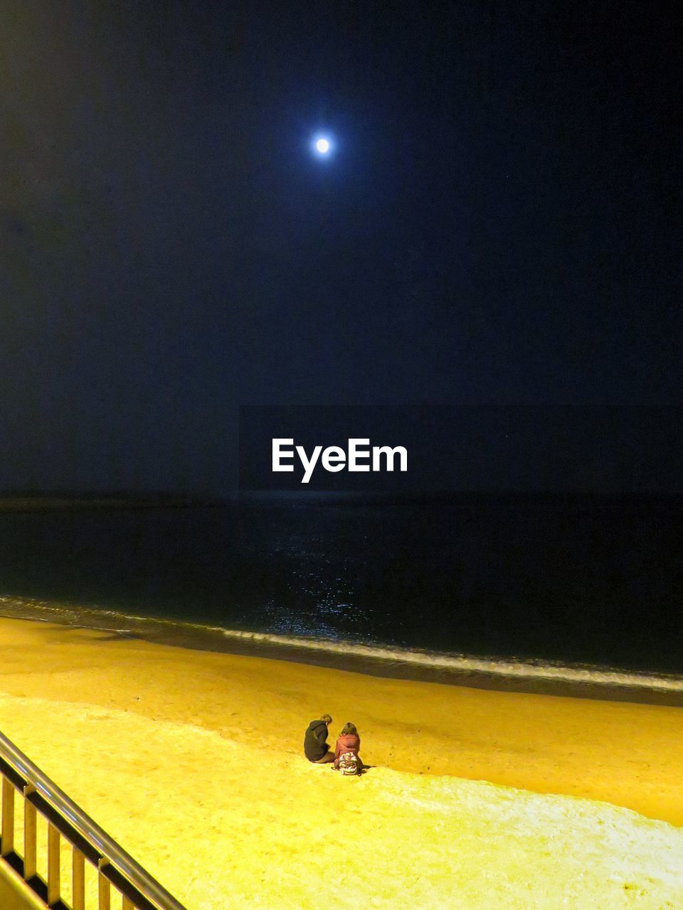 PEOPLE IN SEA AGAINST MOON AT NIGHT