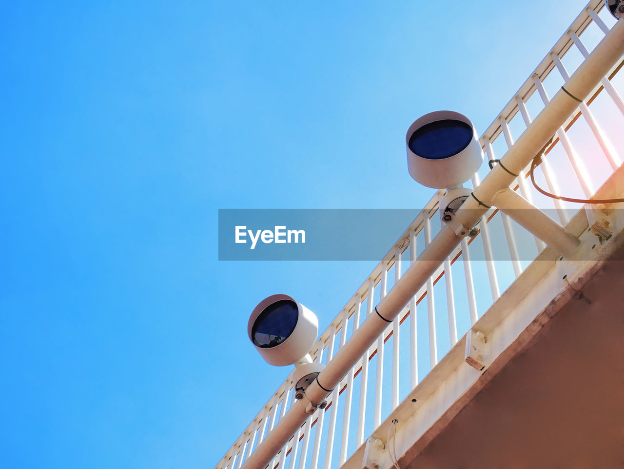 Low angle view of outdoor electric lamps against clear blue sky