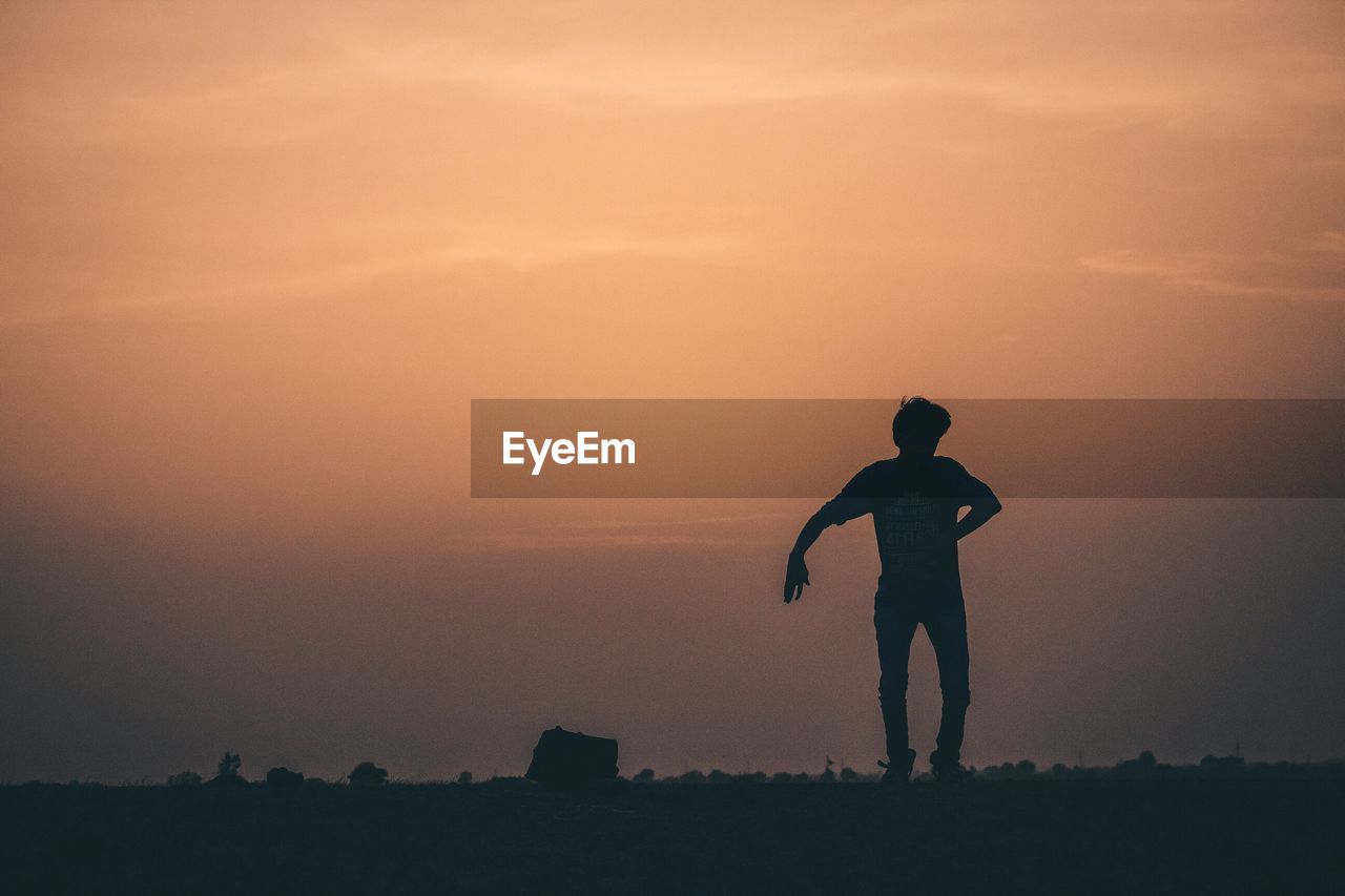 Silhouette man jumping against sky during sunset