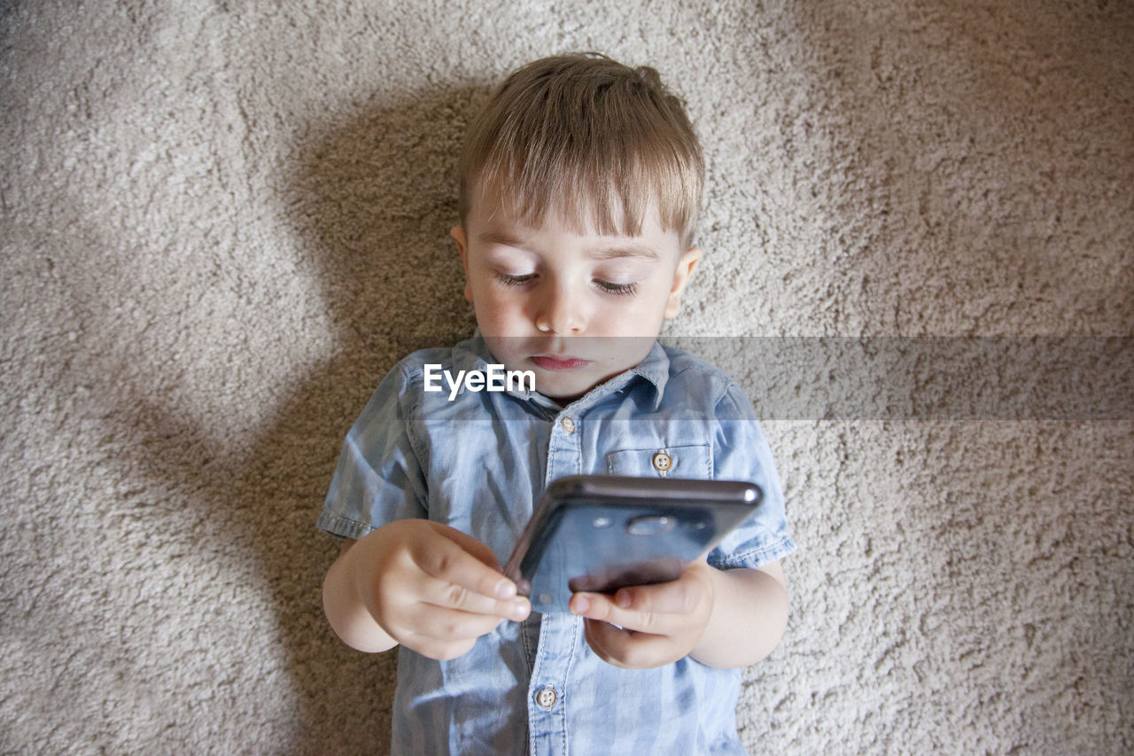 PORTRAIT OF BOY LOOKING THROUGH MOBILE PHONE