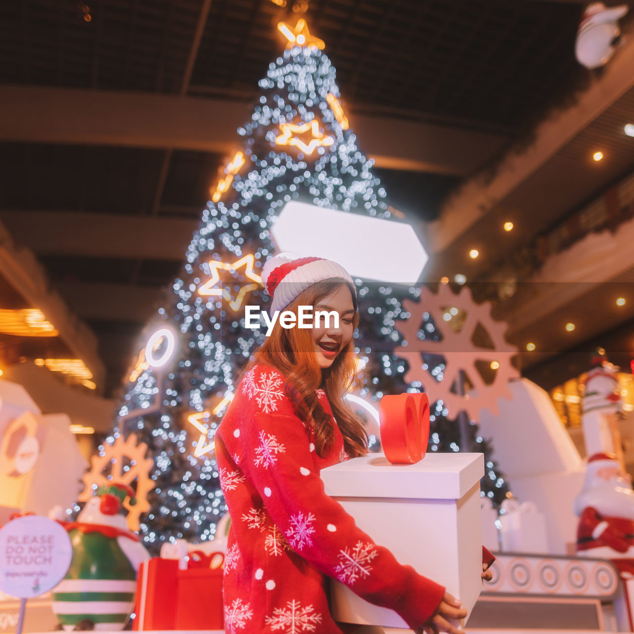 portrait of young woman standing against christmas tree at night