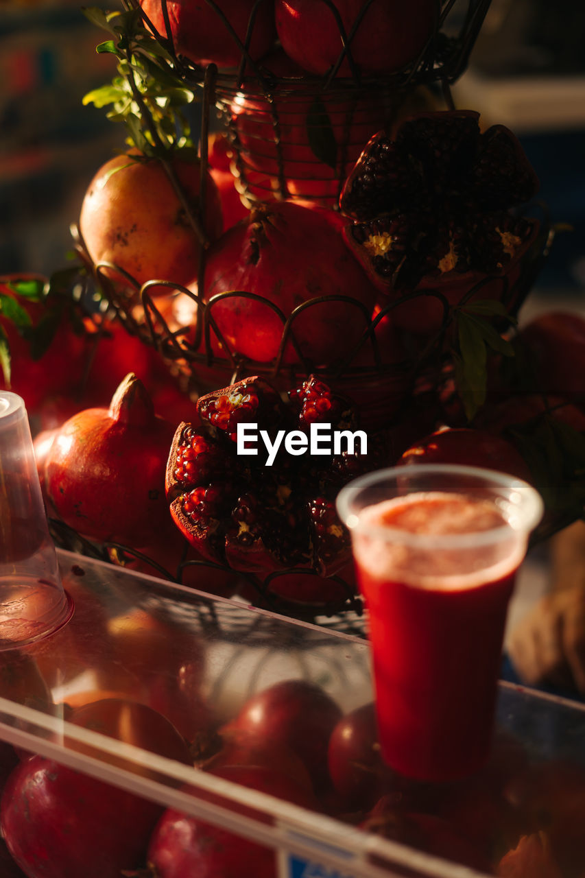 Glass full of pomegranate juice with pomegranates in the back