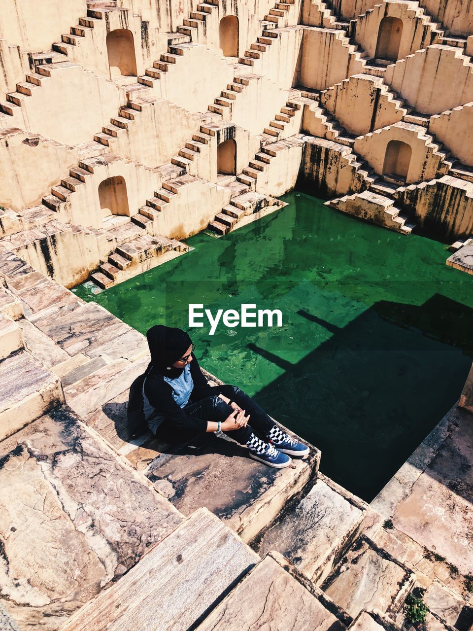 High angle view of woman sitting on built structure