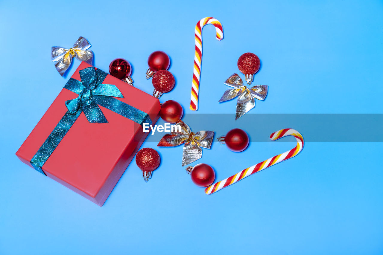 Christmas red balls and a red gift with a ribbon, with lollipops on a blue background.