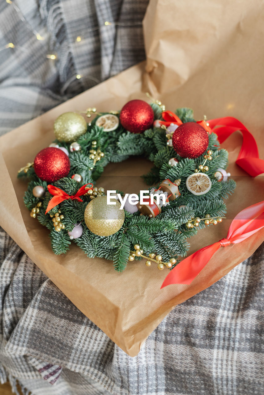 Beautifully decorated christmas wreath in wrapping paper lies on a sofa. christmas preparation.