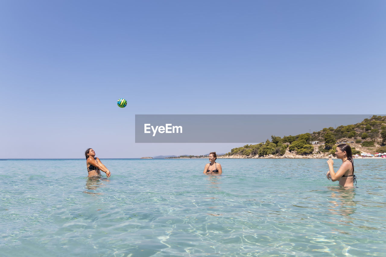 Happy teenagers playing volleyball in water at the vacation and fun