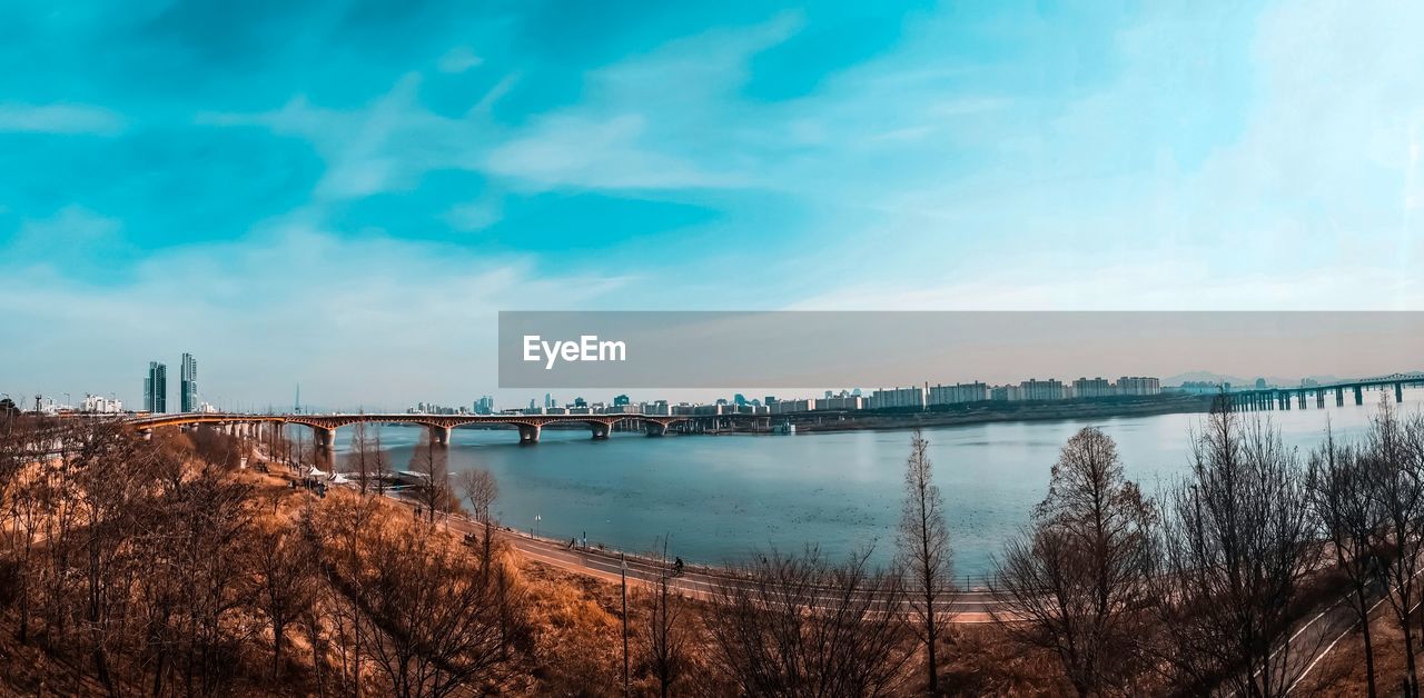 Bridge over river in city against sky