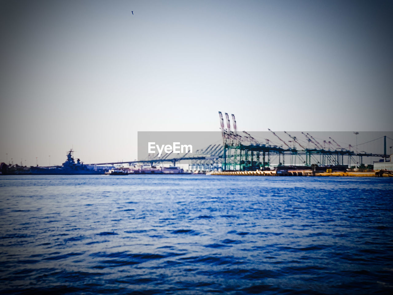 CRANES IN COMMERCIAL DOCK AGAINST CLEAR SKY