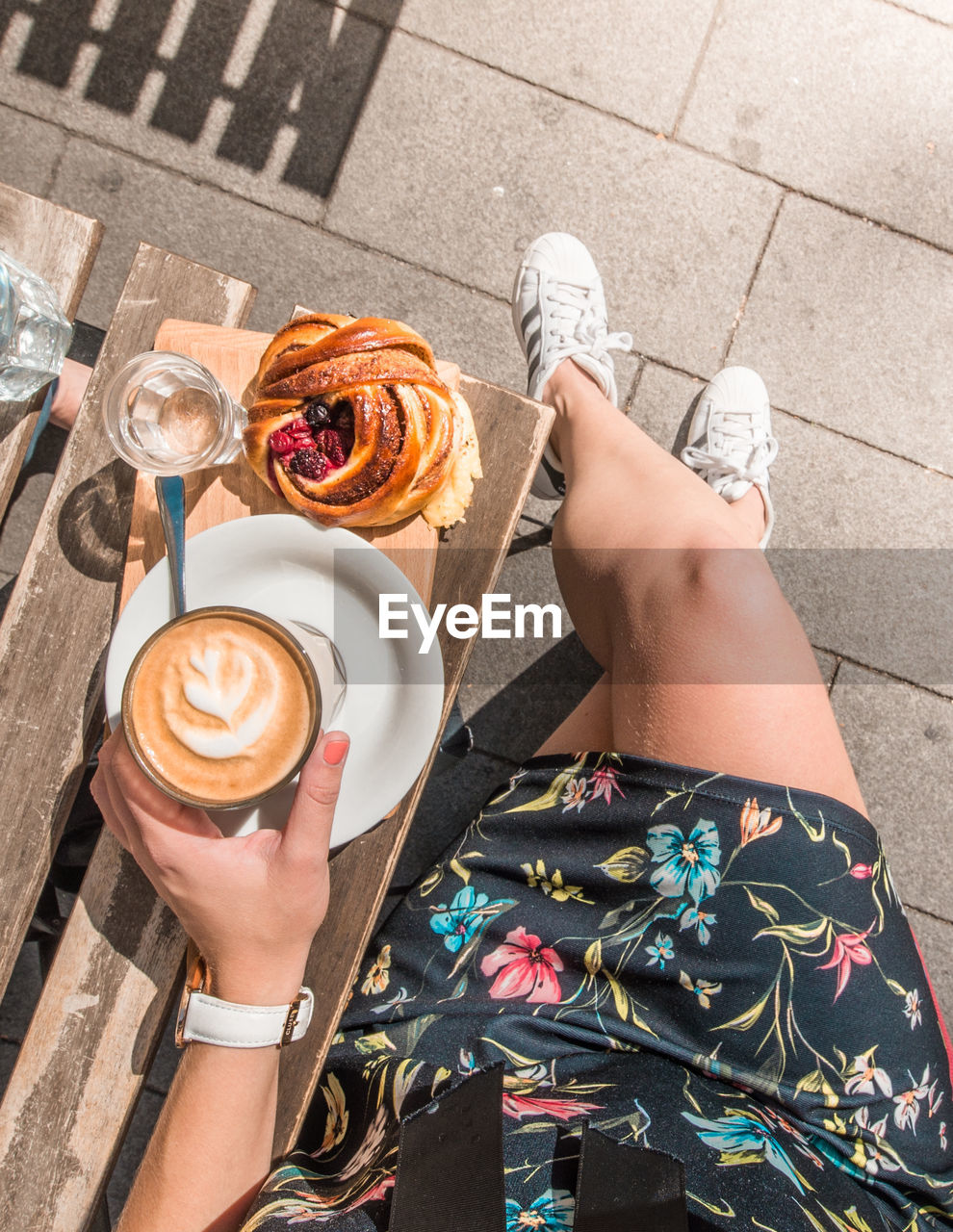 Low section of woman holding coffee cup outdoors