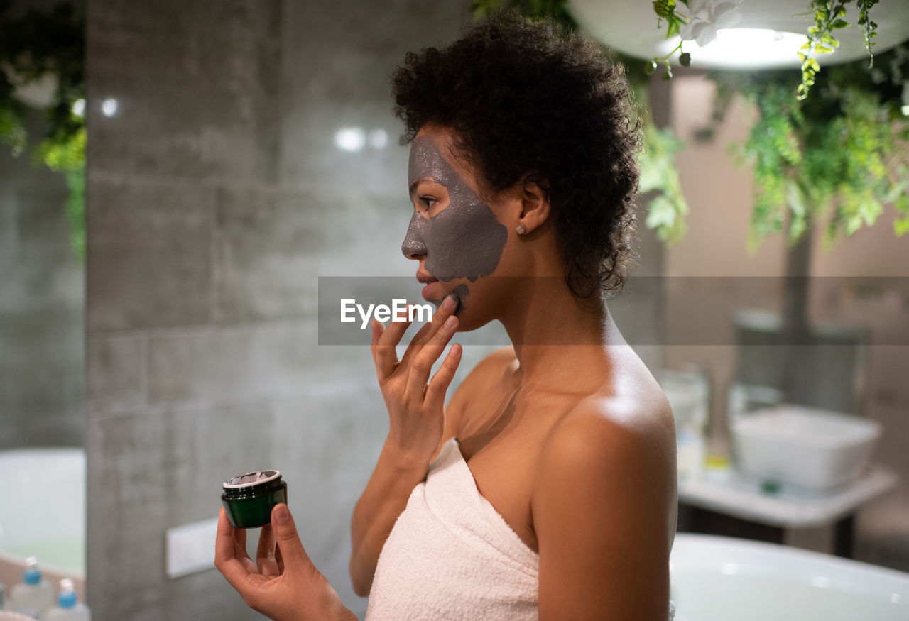 African american woman smearing clay mask