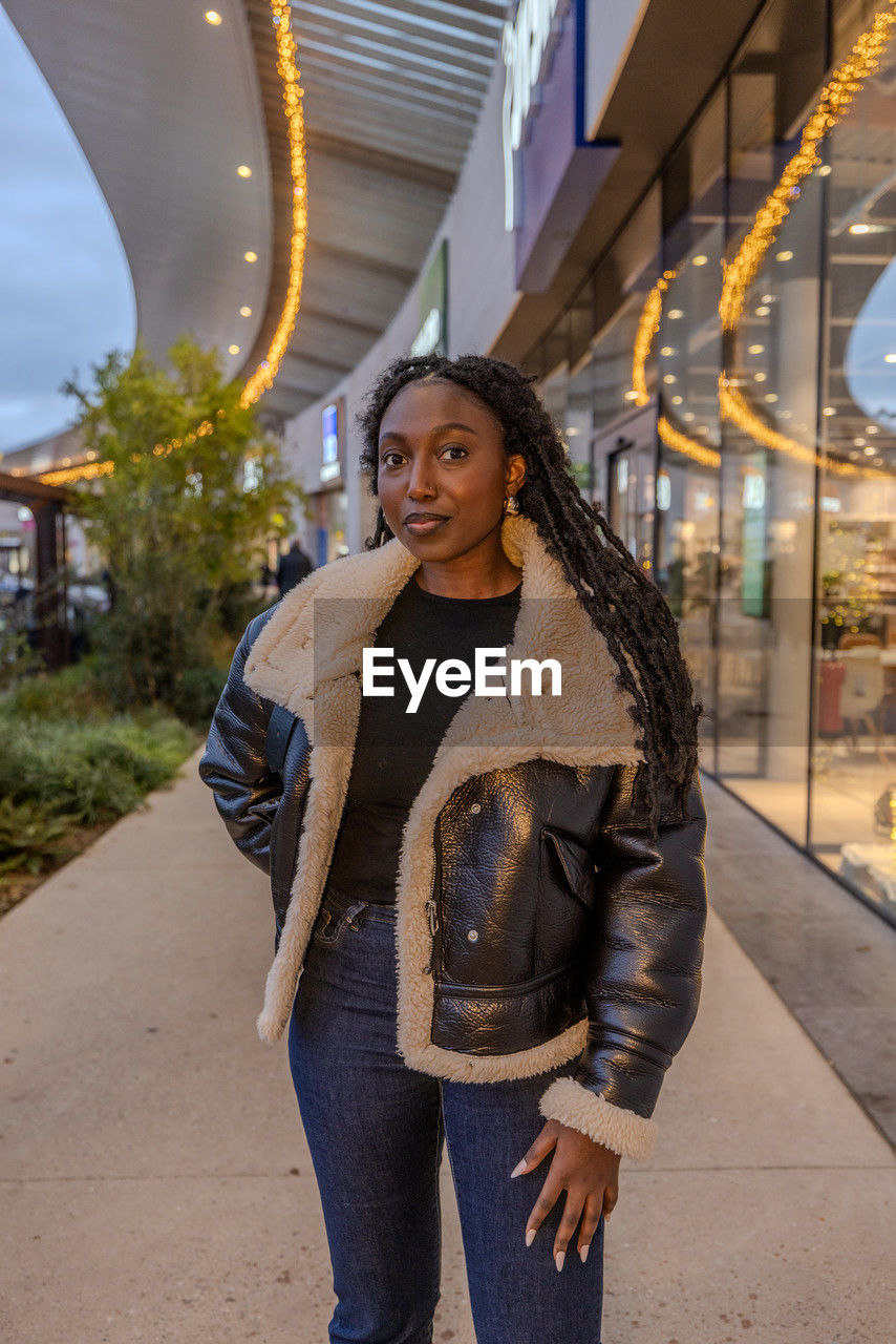 portrait of smiling young woman standing on street