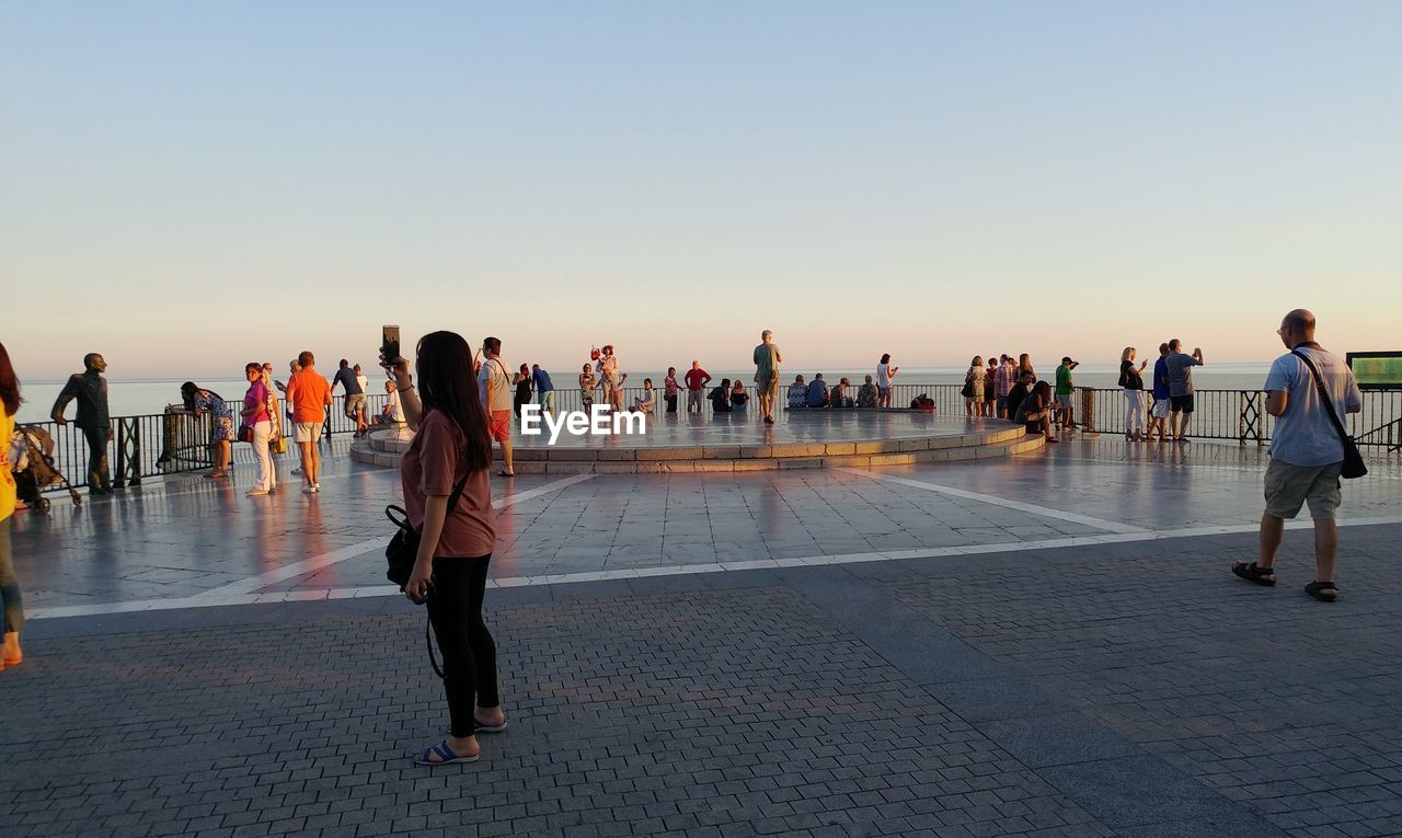 PEOPLE WALKING ON BEACH AGAINST CLEAR SKY