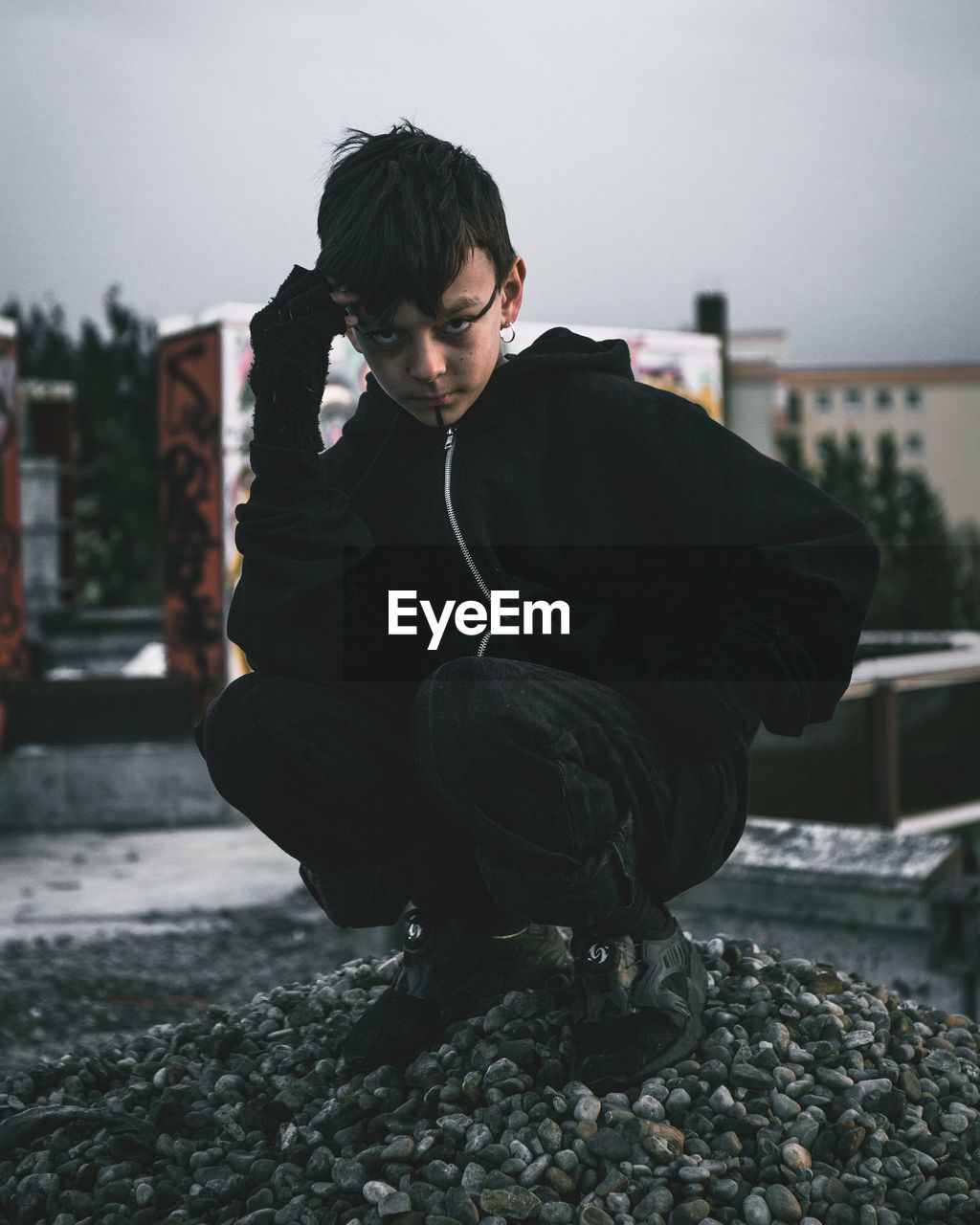 Full length portrait of boy crouching against building