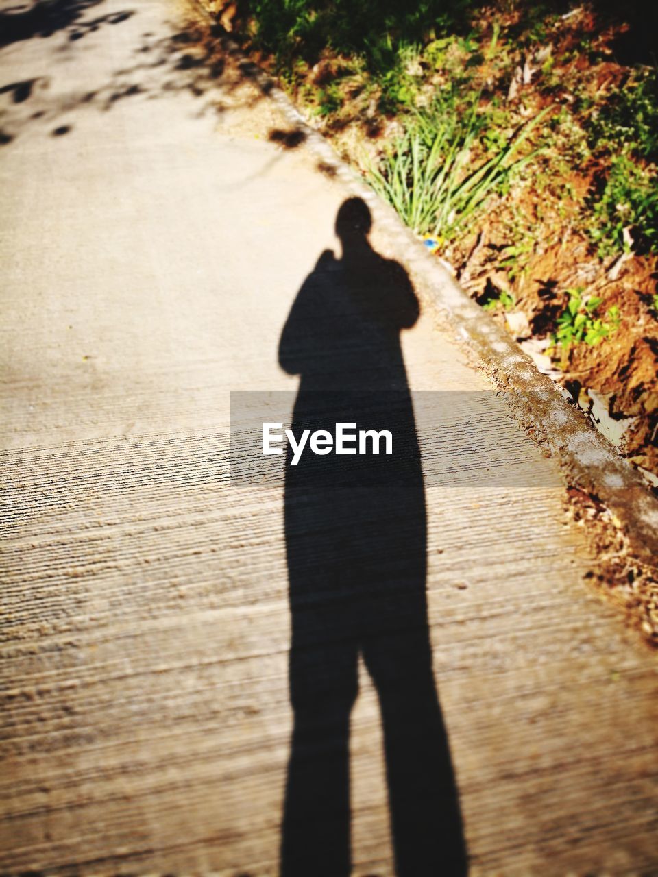 REAR VIEW OF SILHOUETTE MAN WALKING ON COBBLESTONE