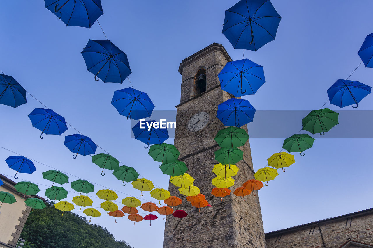 LOW ANGLE VIEW OF MULTI COLORED UMBRELLAS HANGING AGAINST CLEAR BLUE SKY