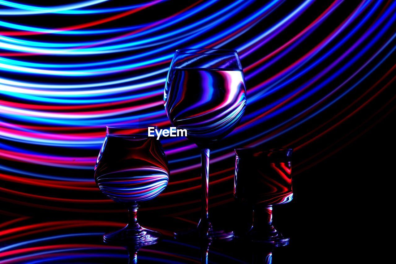 Close-up of drinks in wineglasses with light painting against black background