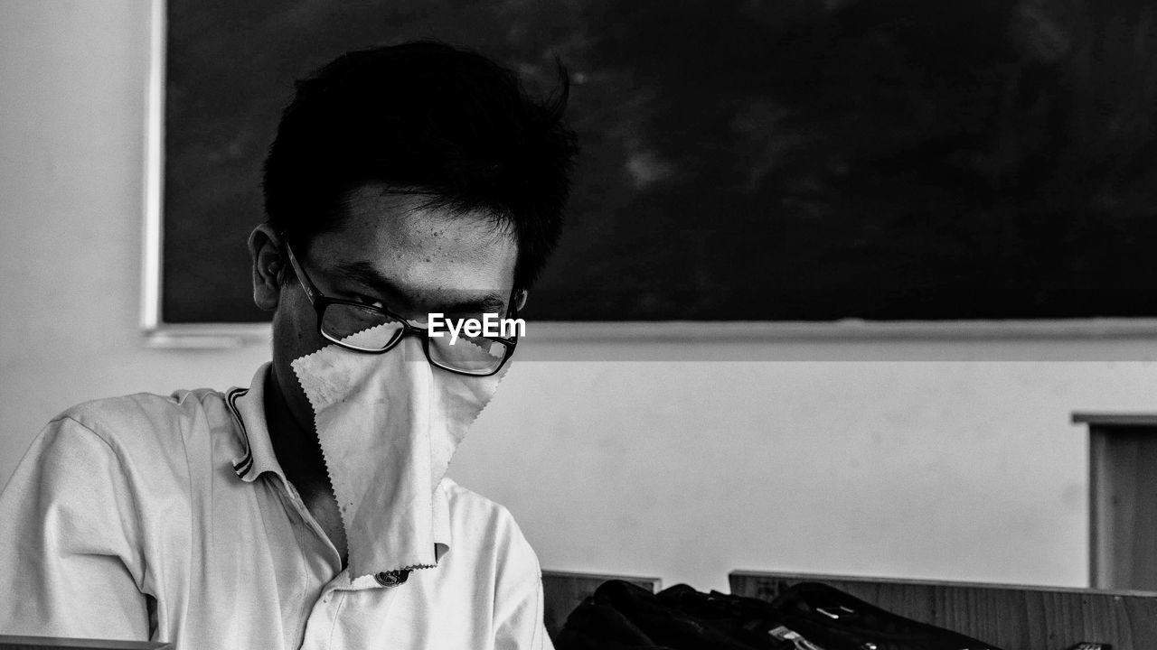 Portrait of teenage boy with fabric on face in classroom