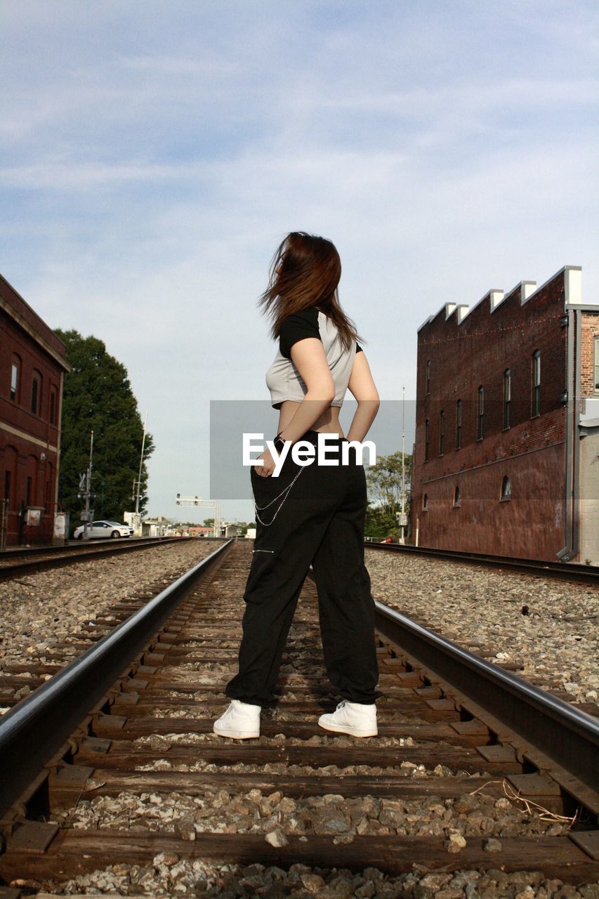 side view of young woman standing on railroad station