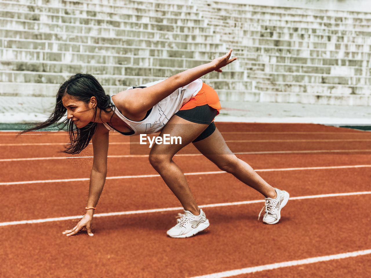 Side view of woman exercising on sports track