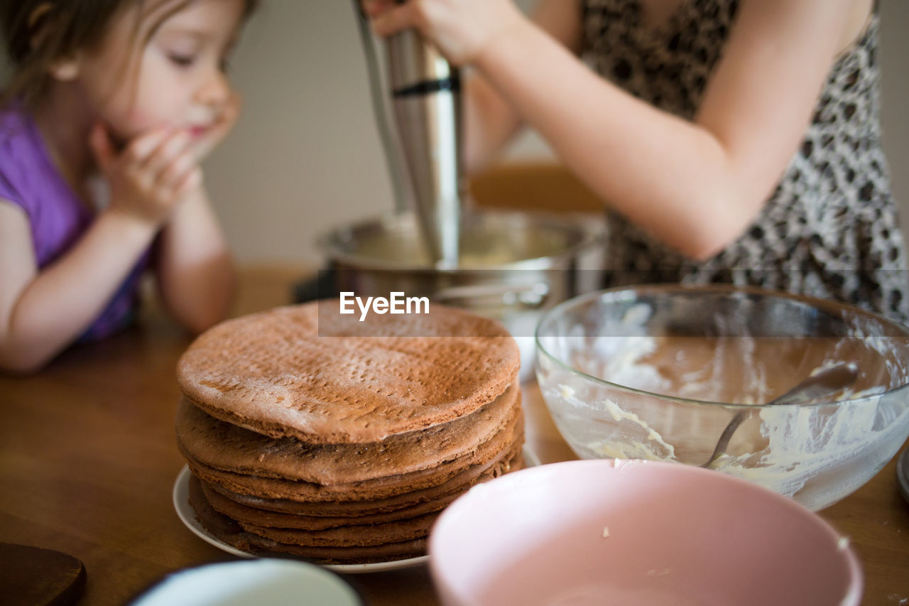 Midsection of woman preparing food with daughter on table