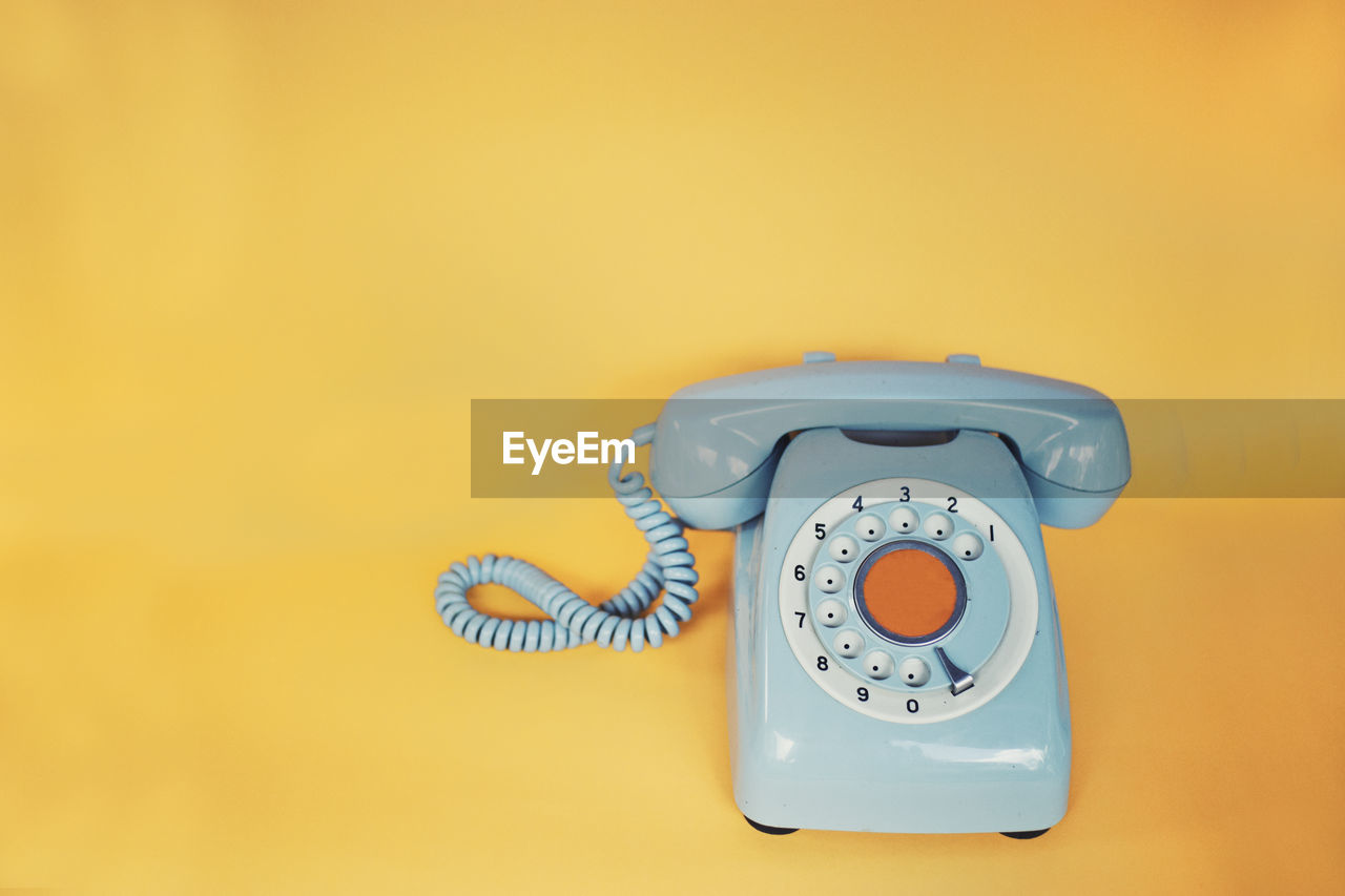 Close-up of telephone booth against yellow wall