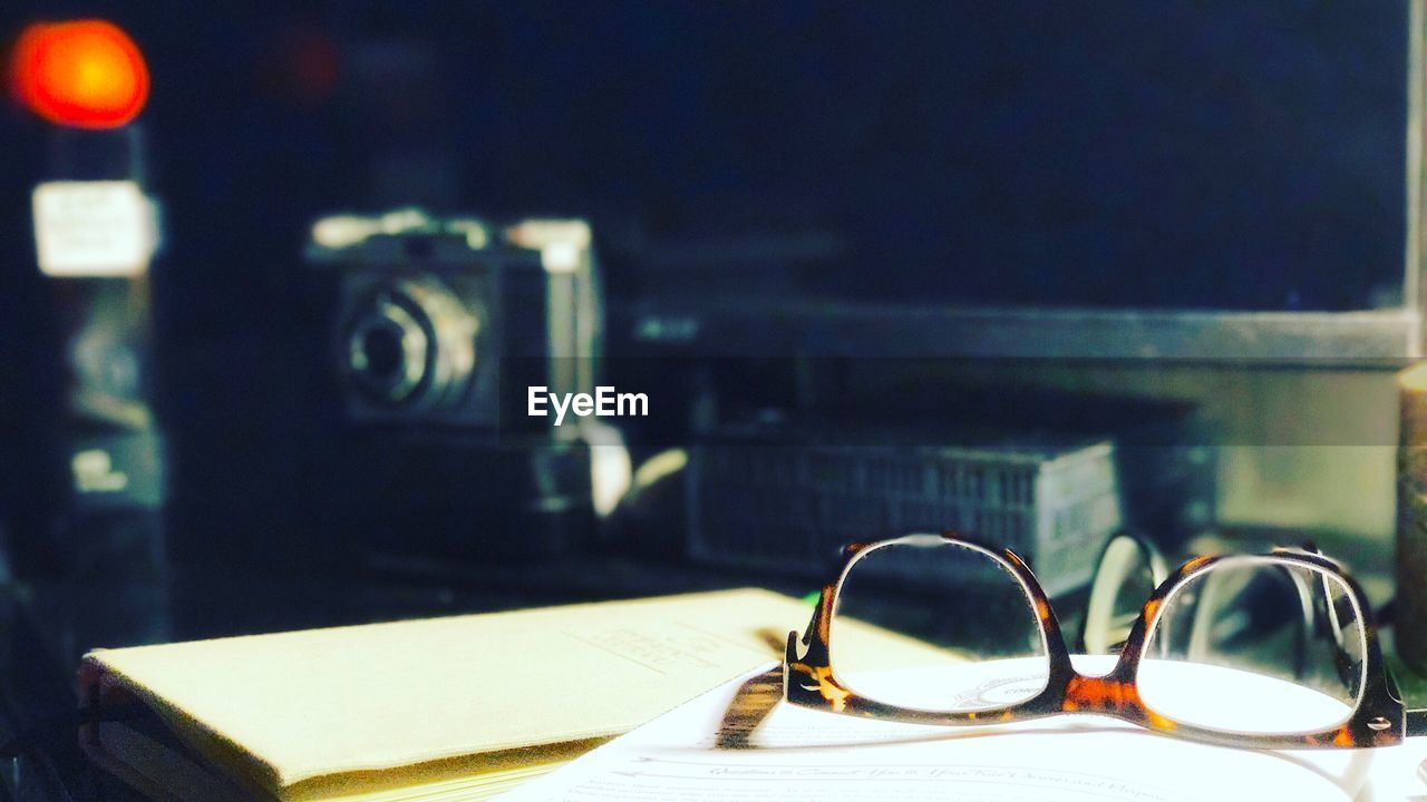 CLOSE-UP OF EYEGLASSES ON TABLE WITH LIGHT