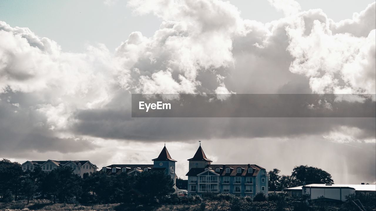 View of buildings in town against cloudy sky