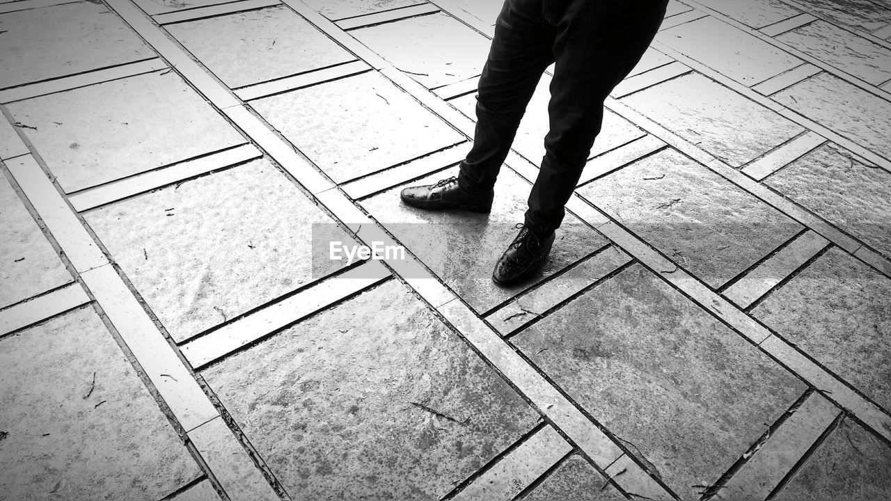 Low section of man standing on tiled floor