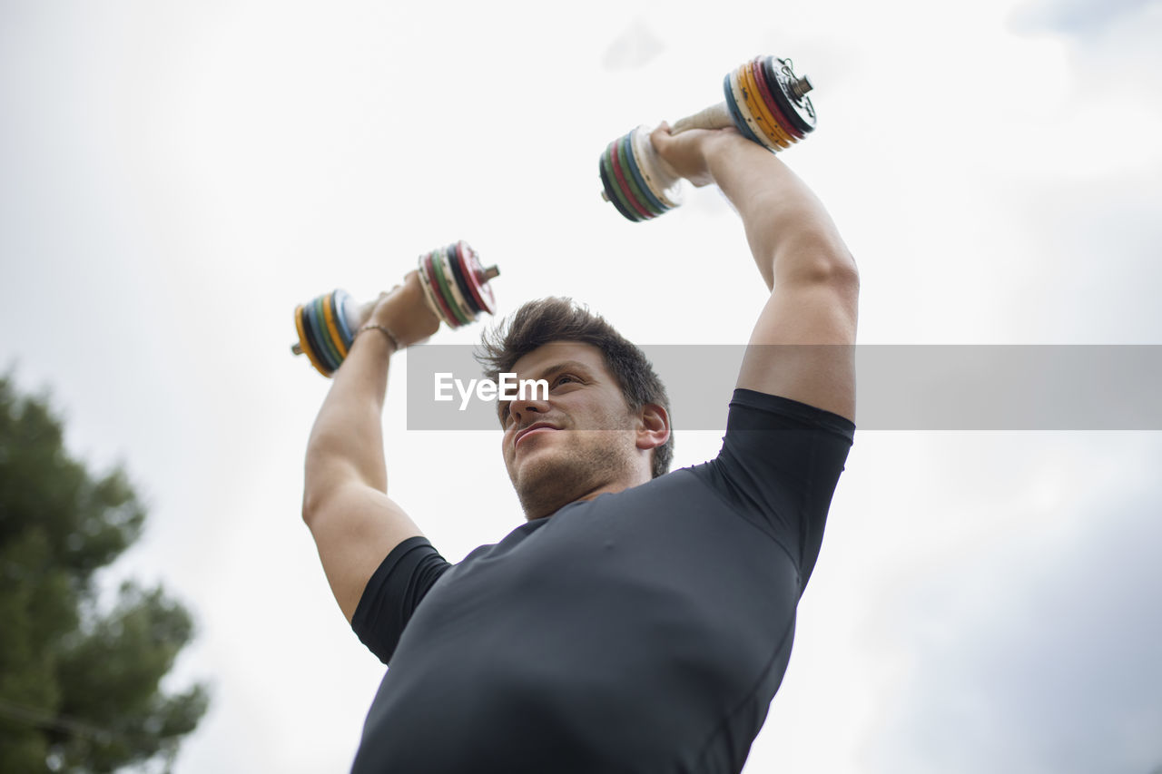 Low angle view of man exercising against sky