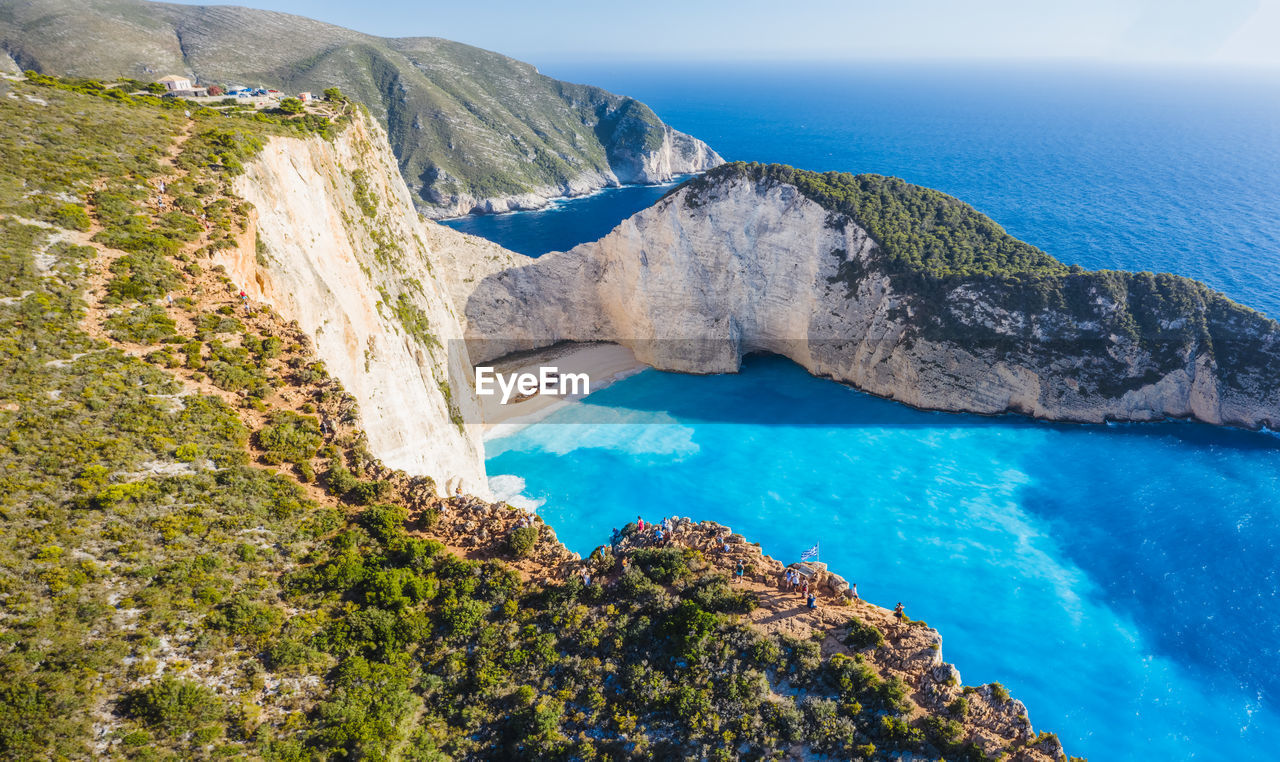 HIGH ANGLE VIEW OF ROCKS ON SEA SHORE AGAINST SKY