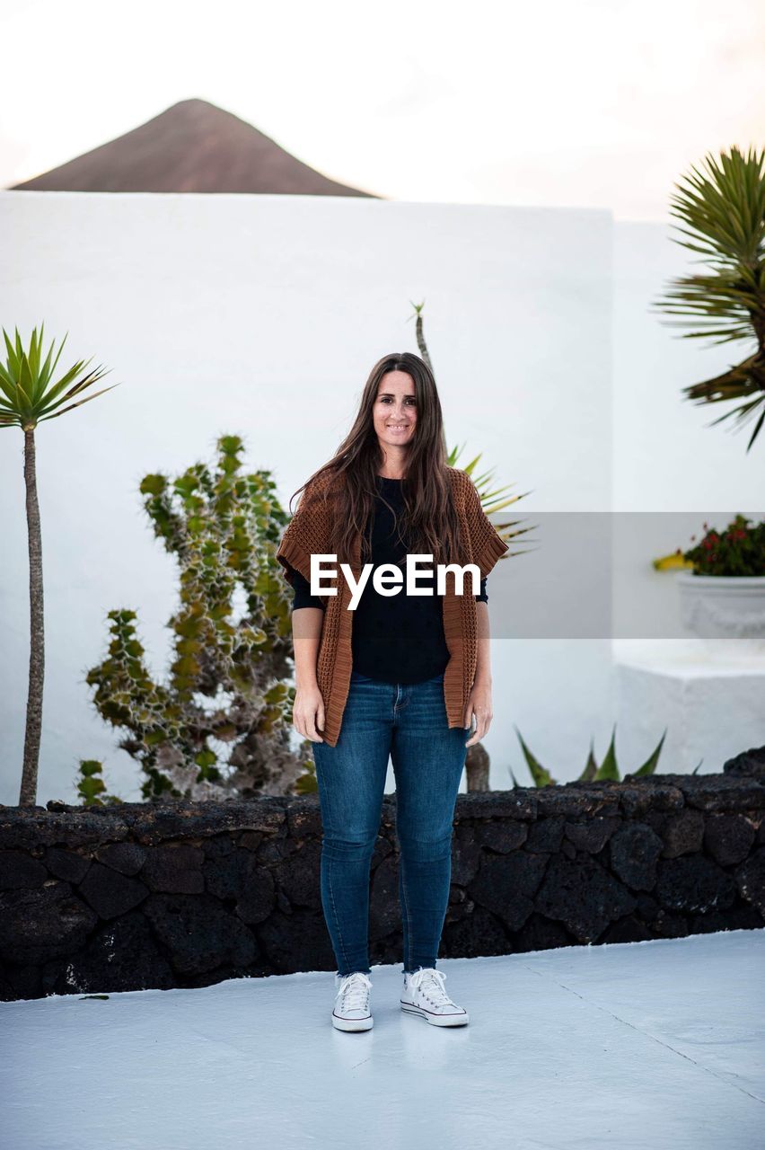 Portrait of smiling woman standing against wall