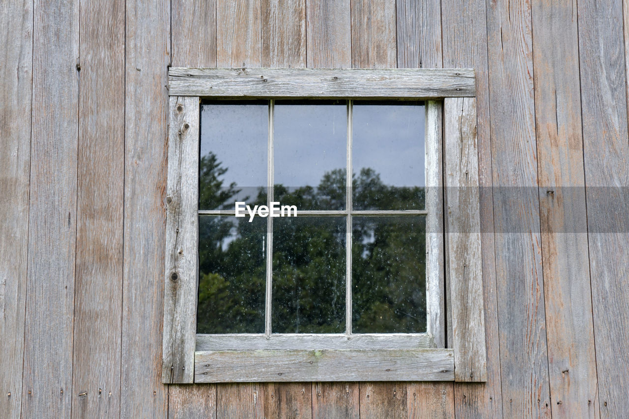 Old weathered wooden barn window reflection