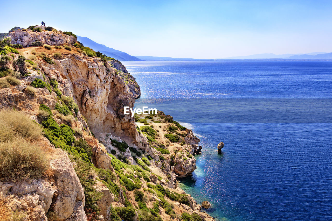 Calm turquoise waves wash the rocky shore of the gulf of corinth in the ionian sea.