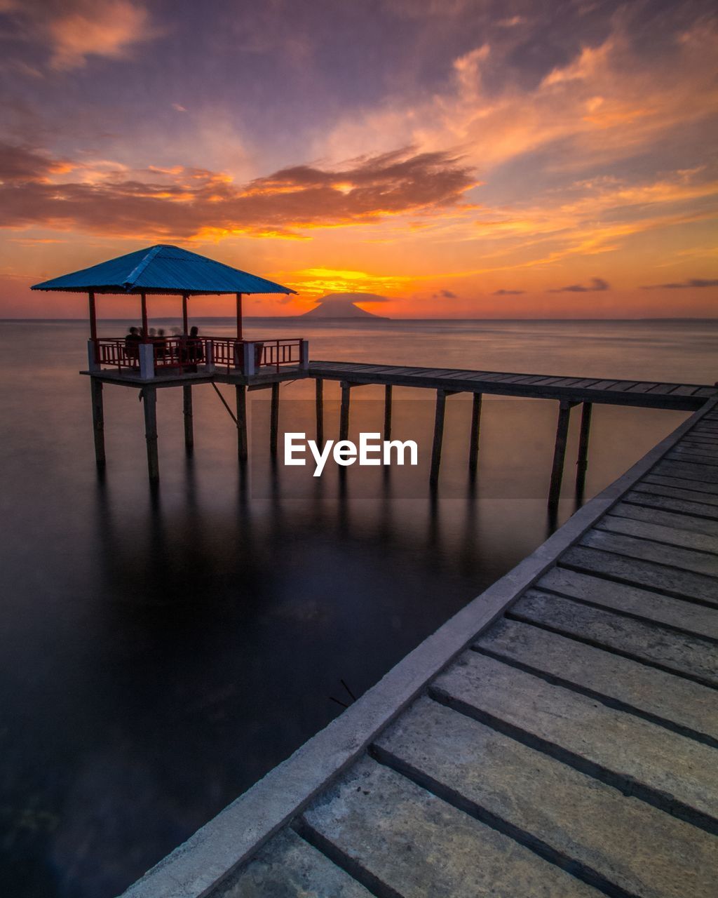 Pier over sea against sky during sunset