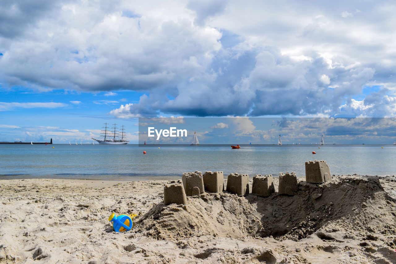 Sandcastles at beach against cloudy sky