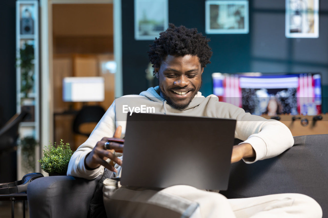 young man using laptop while sitting on table