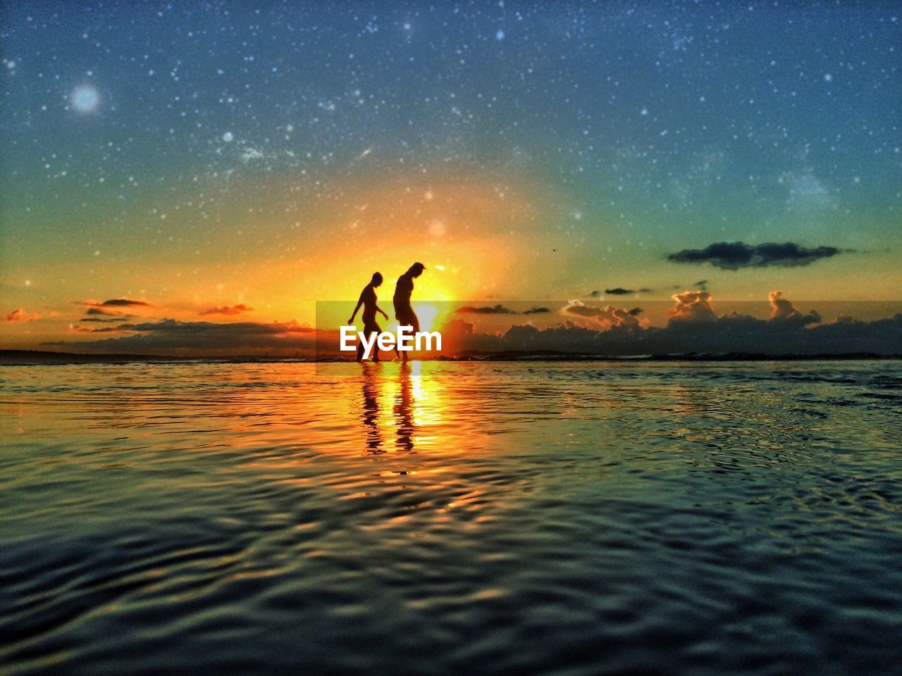 Low angle view of silhouette man and woman walking on beach