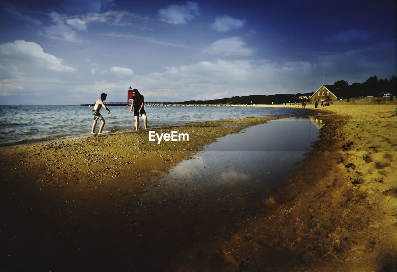 MEN STANDING ON BEACH AGAINST SEA