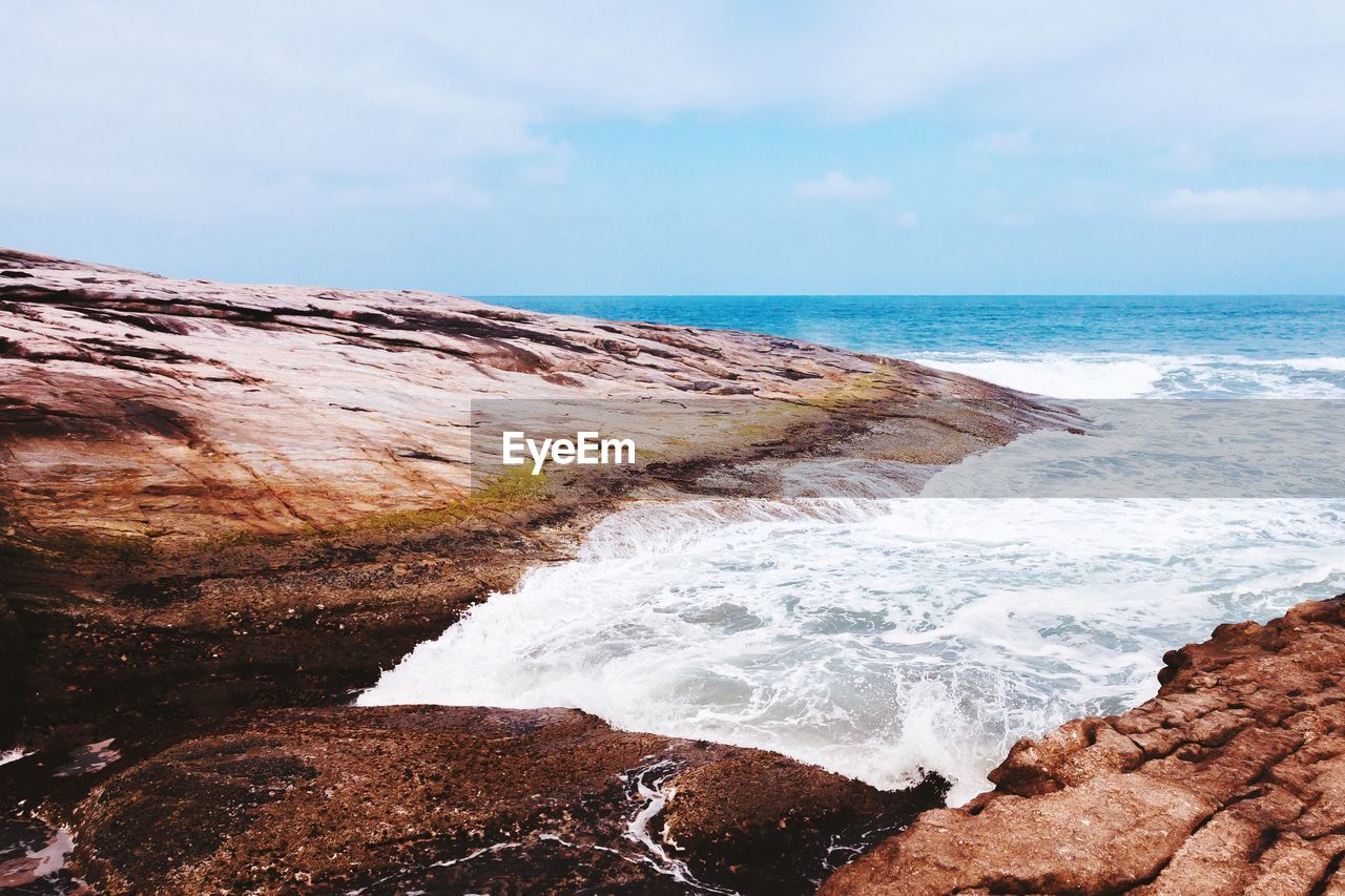 Rocky sea shore against sky