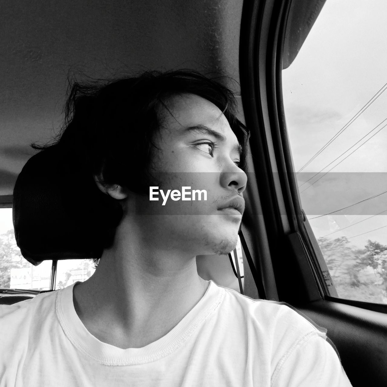 PORTRAIT OF TEENAGE BOY LOOKING THROUGH WINDOW