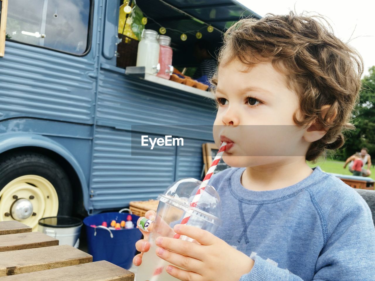Close-up of cute boy drinking lemonade while looking away outdoors