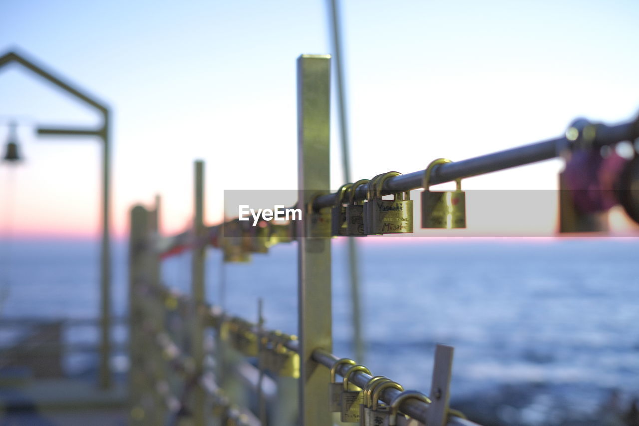 METALLIC RAILING BY SEA AGAINST SKY