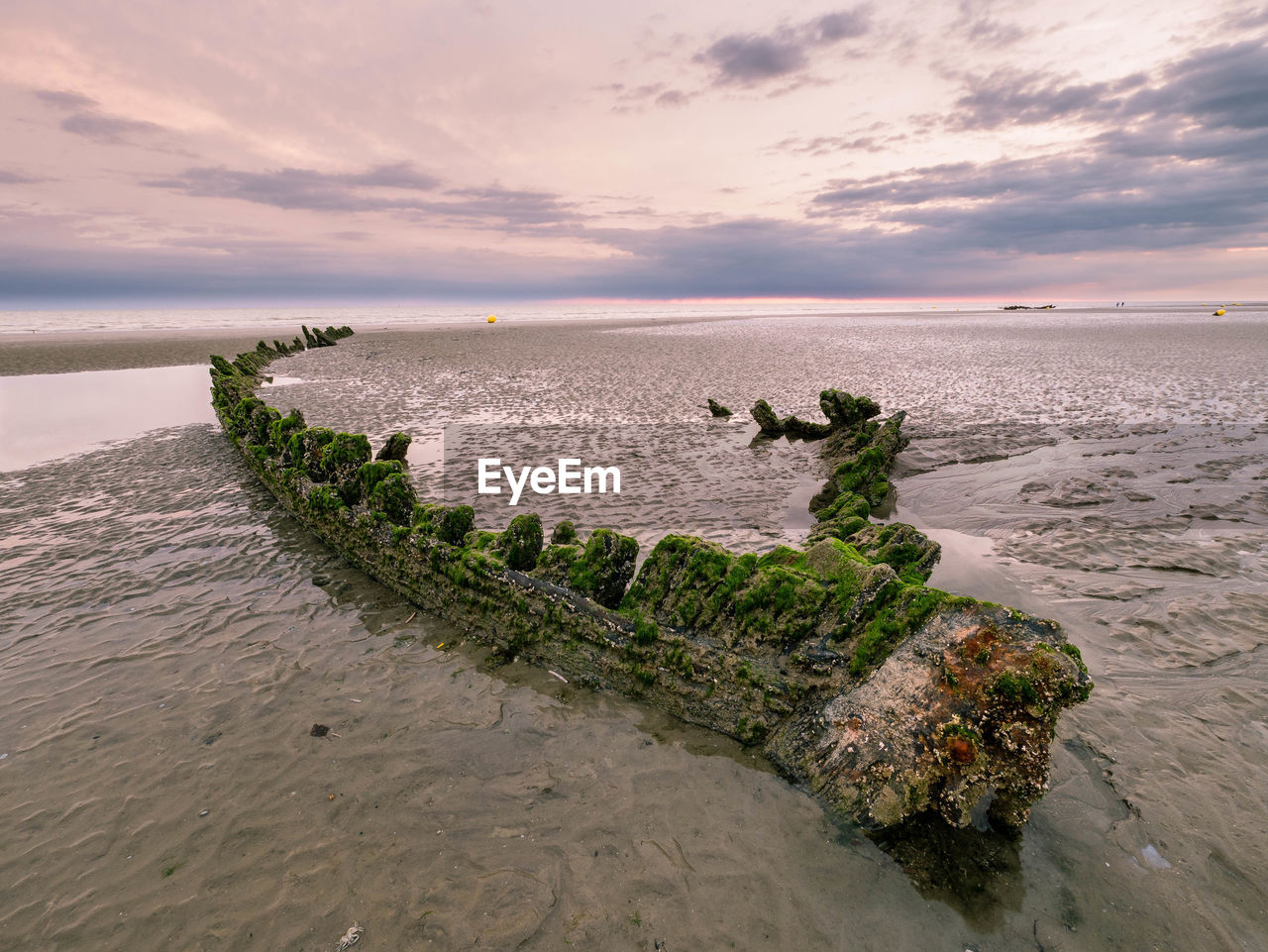 Wreck of a hull from a world war ship at a beach in northern france at sunrise