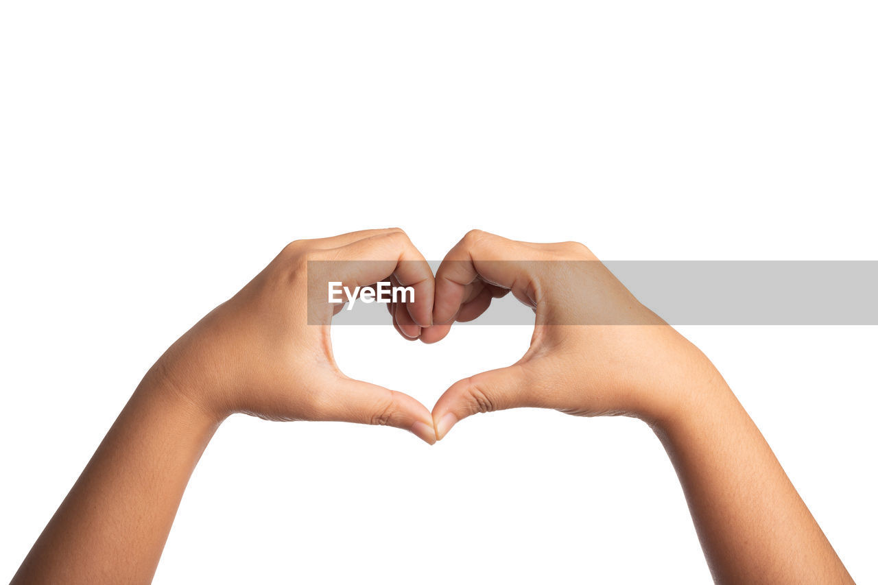 Close-up of hands making heart shape against white background