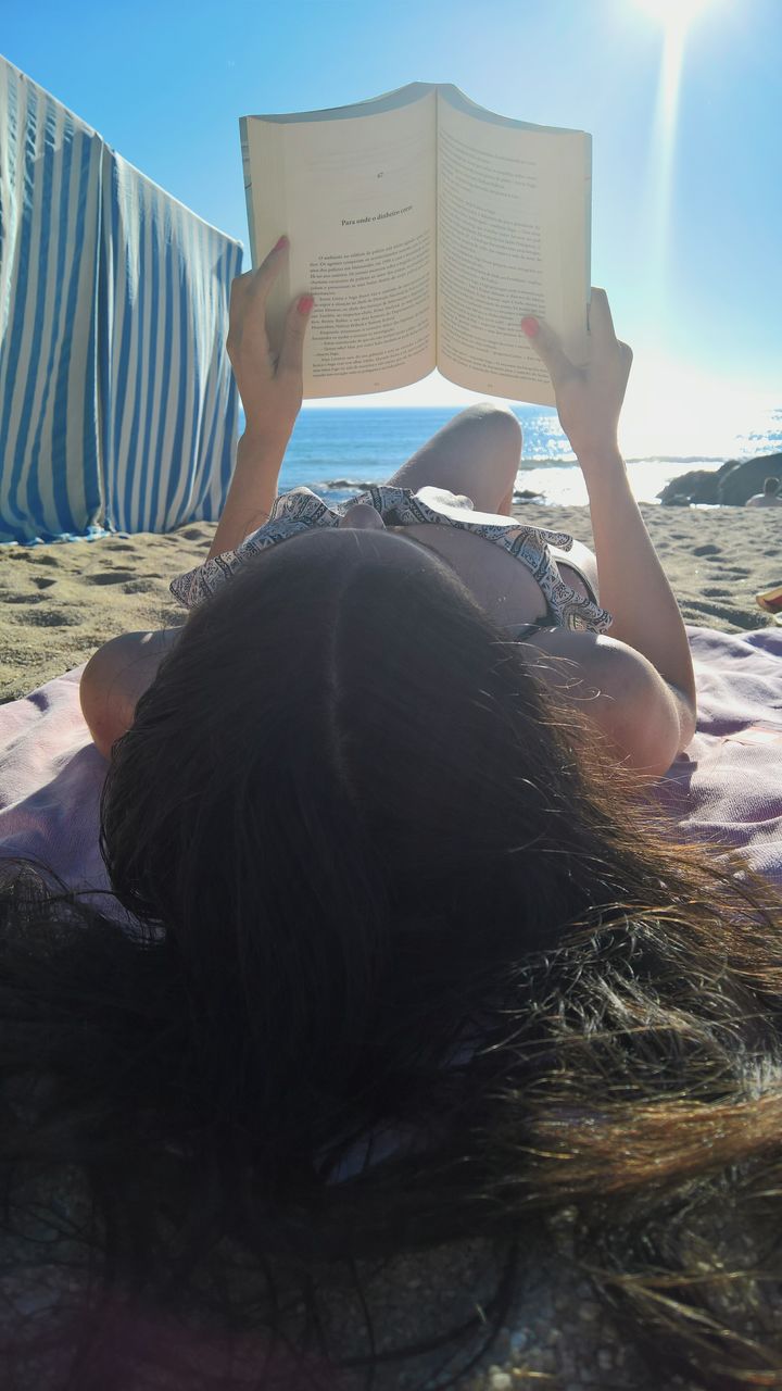 MIDSECTION OF MAN READING BOOK AGAINST BUILDING