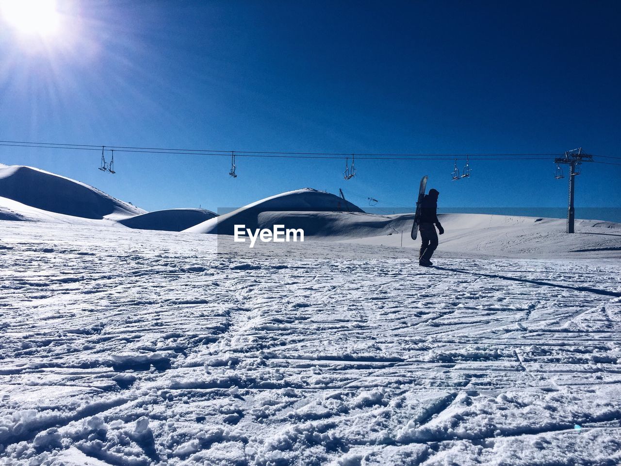 Man on snow covered landscape against clear blue sky