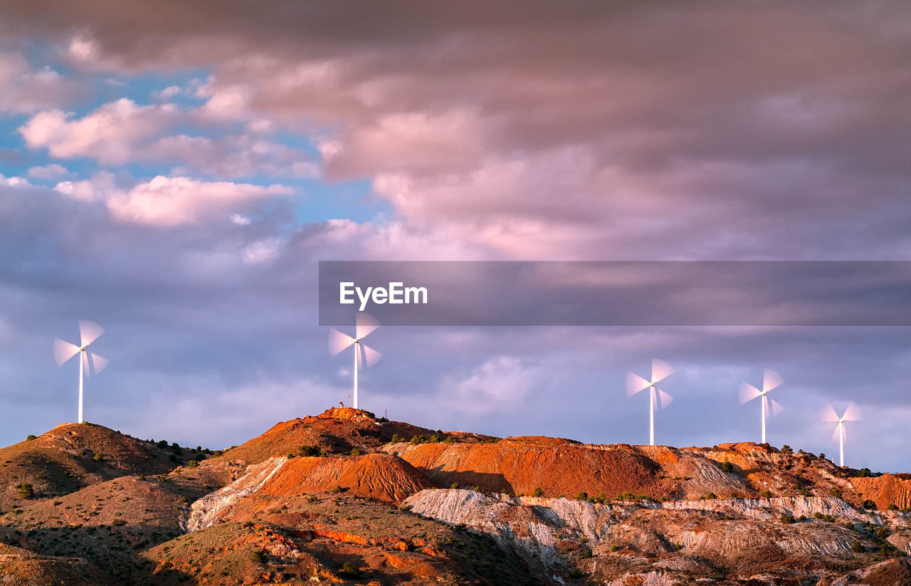 Wind turbines on mountain against sky