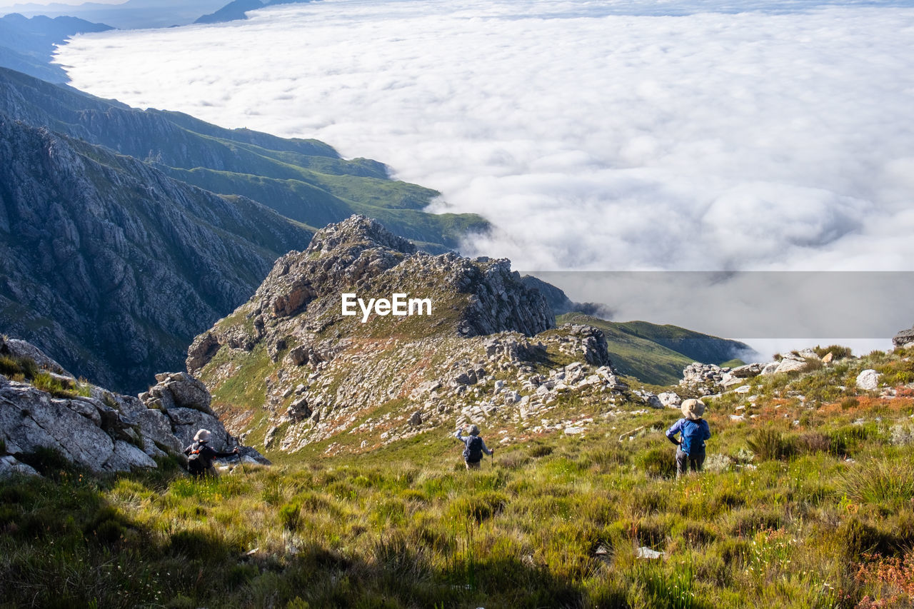 Three hikers looking at mountain ranges  and sea of clouds 